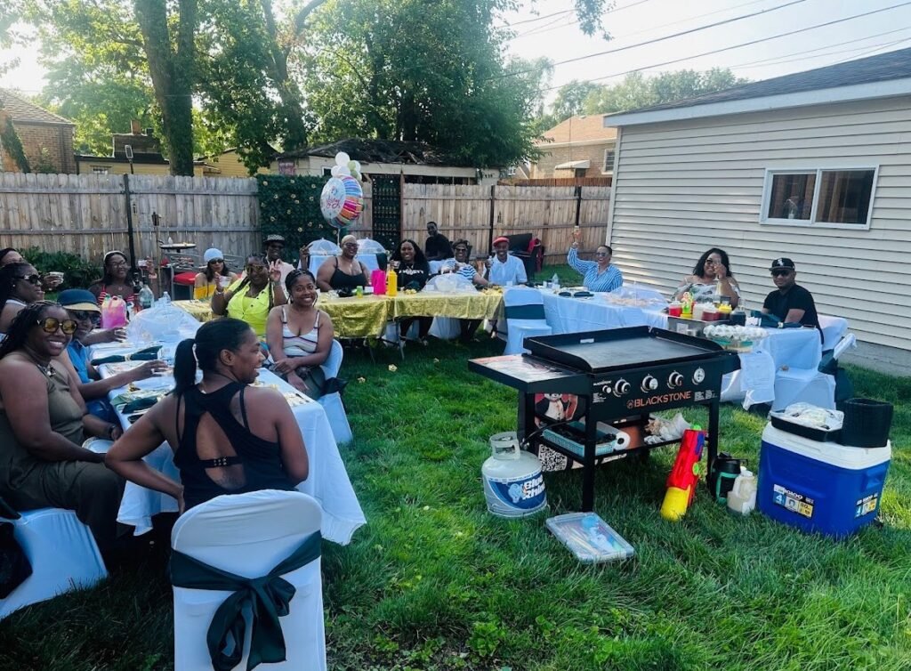 Group enjoying an outdoor Hibachi party with live cooking setup, delicious food, and festive decorations.